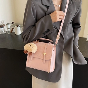 Rosa Umhängetasche aus Glattleder und Samt, getragen von einem Modell über Blazer