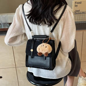 Retro Damen Rucksack aus schwarzem Leder mit Plüschanhänger am Modell im Café