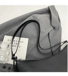 Detail of smooth black faux leather shoulder bag with sleek silver zipper and long straps