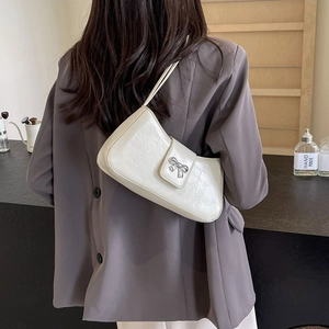 Elegante cremeweiße Baguette-Tasche mit silberner Schleifenschnalle an der Schulter