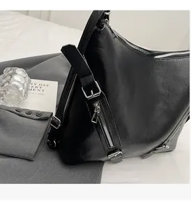 Detail shot of large black tote bag with glossy finish and silver metal zippers