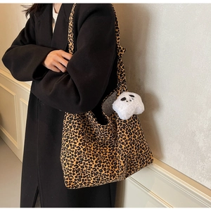 Detailed view of large leopard print tote bag with a cute plush panda keychain