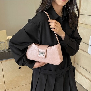 Schicke rosa Baguette-Schultertasche mit silberner Schleifenschnalle, getragen von Modell