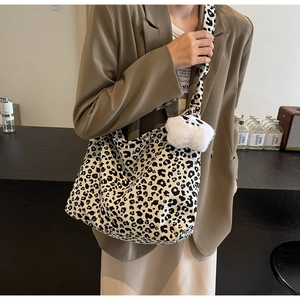 Close-up of leopard print shoulder bag featuring a cute white plush cat charm pendant
