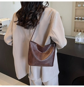 Detail of dark brown leather tote featuring minimalist embossed text and knotted shoulder strap