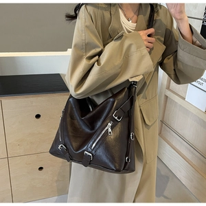 Detail of dark brown vintage faux leather tote bag with metal zippers on a khaki trench coat