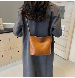 Detail of brown leather bucket bag with Fashion and Sunday embossed text and premium texture