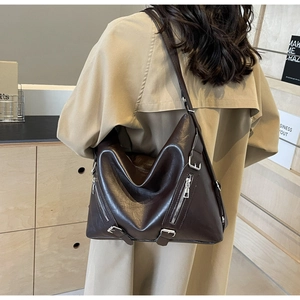 Detail view of large dark brown hobo bag with silver zippers on a khaki trench coat