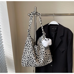 Detail of leopard print tote bag with white plush charm and knotted shoulder strap