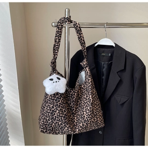 Detail of leopard print tote bag with a white plush star charm and canvas texture