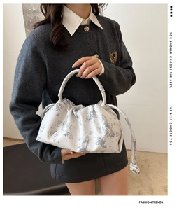 Detail of white pleated handbag featuring subtle grey butterfly print and drawstring design