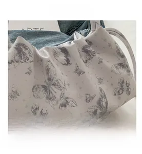 Detail of canvas bucket bag featuring delicate butterfly prints and drawstring texture