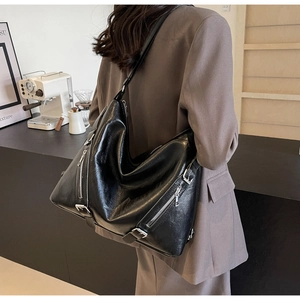 Chic black tote bag in glossy finish shown in a stylish cafe setting for winter 2025
