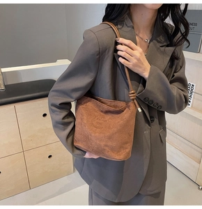 Detail of a brown suede bucket bag featuring a knotted strap and Fashion and Sunday text