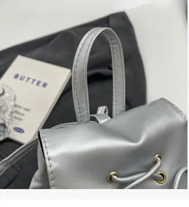Detailed close-up of metallic silver backpack with golden hardware and durable handle