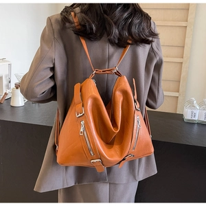 Detail of soft orange leather shoulder bag with decorative metal zippers and buckles