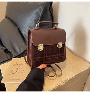 Detail of vintage brown PU leather and plaid fabric handbag with metal buckles