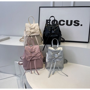 Vue détaillée de quatre sacs à dos en cuir texturé blanc, noir, rose et argent avec nœuds