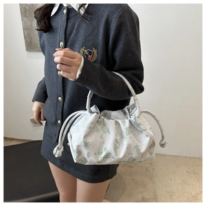 Detail view of white butterfly print pleated bag with drawstring closure and top handle