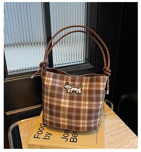 Detailed close-up of brown checkered bucket bag with embroidered dachshund pattern and leather straps