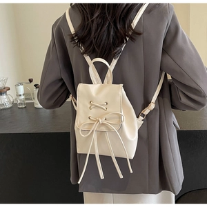 Gros plan sur le sac à dos en cuir blanc cassé avec un nœud décoratif à lacets croisés