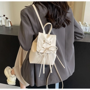 Detail shot of a cream white mini backpack with a stylish drawstring bow and PU leather texture