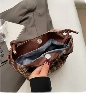 Detail view of the brown plaid bucket bag showing interior magnetic snaps and drawstring