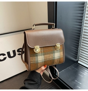 Detail of tweed checkered texture and brown leather flap with retro gold buckles
