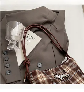 Detail of checkered shoulder bag featuring dachshund embroidery and knotted leather handle