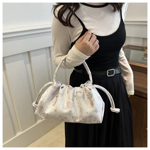 Close-up of white cloud bag featuring elegant butterfly prints and pleated drawstring detail