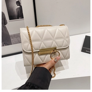 Detail of white quilted chain bag with gold ring clasp and elegant stitch texture