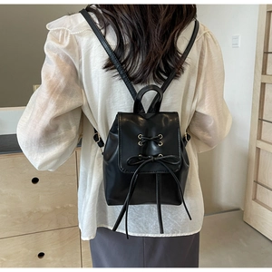Rear view of a black mini leather backpack with bow-knot and metal eyelet detailing