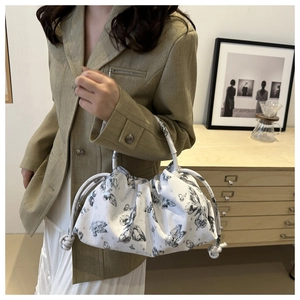 Close-up of white butterfly print pleated dumpling bag styled with an autumn outfit