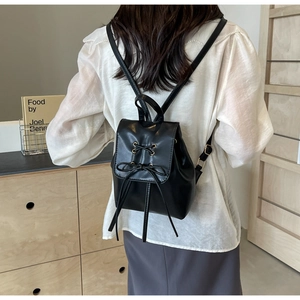 Détail d'un mini sac à dos en cuir noir avec nœud décoratif et fines bretelles réglables