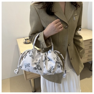 Close-up of pleated handbag with black butterfly print and decorative side drawstring knot
