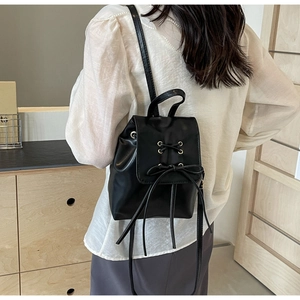 Chic black mini leather backpack with stylish lace-up metal eyelets and a decorative bow