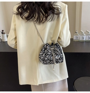 Detailed view of silver sequins bucket bag with metal chain and large pearl drawstring