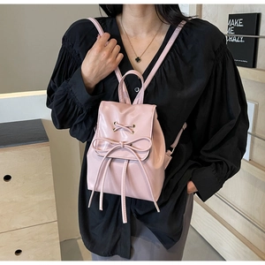 Detail of pink PU leather mini backpack featuring bow drawstring and gold metal eyelets