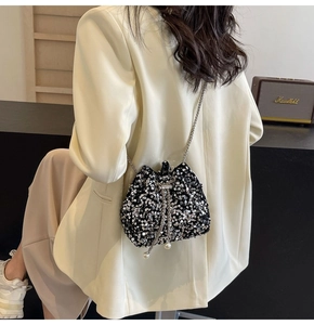 Detail of black sequin bucket bag featuring silver chain strap and pearl drawstring charms