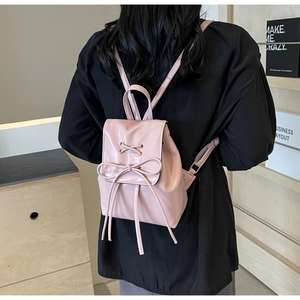 Vue arrière d'un mini sac à dos rose clair avec nœud porté par un mannequin en intérieur