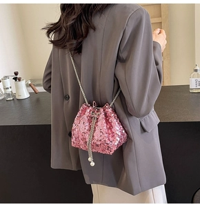 Dettaglio borsa a secchiello con paillettes rosa, catena argento e perla sulla modella