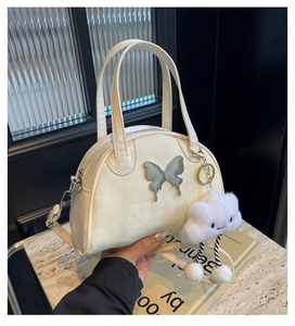 Detail of off-white saddle bag with silver butterfly hardware and plush cloud charm