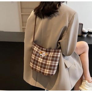 Detail of retro plaid shoulder bag with puppy embroidery and slim leather strap