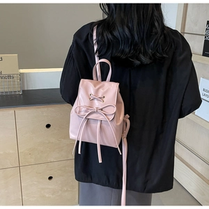Rear view of a model wearing the pink mini backpack with a stylish bow decoration