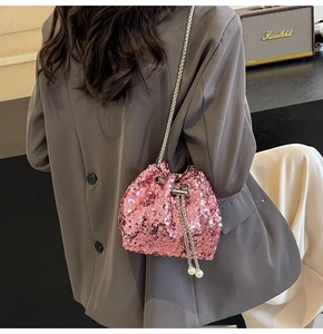 Detail of pink sequin bucket bag featuring pearl drawstring and metallic chain strap