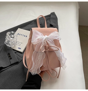 Mini sac à dos rose avec nœud en dentelle blanche sur un arrière-plan esthétique