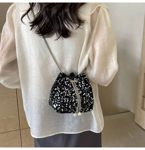 Close-up of sequin bucket bag with silver chain strap and pearl drawstring detail