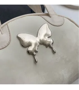 Detailed view of cream leather square bag featuring a silver butterfly metal ornament