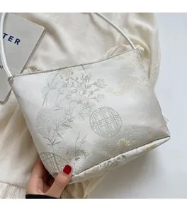 Details des eleganten chinesischen Jacquard-Stoffs und Blumenmusters auf weißer Beuteltasche