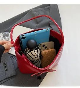Spacious red faux leather bag interior showing a tablet, phone, and folding umbrella